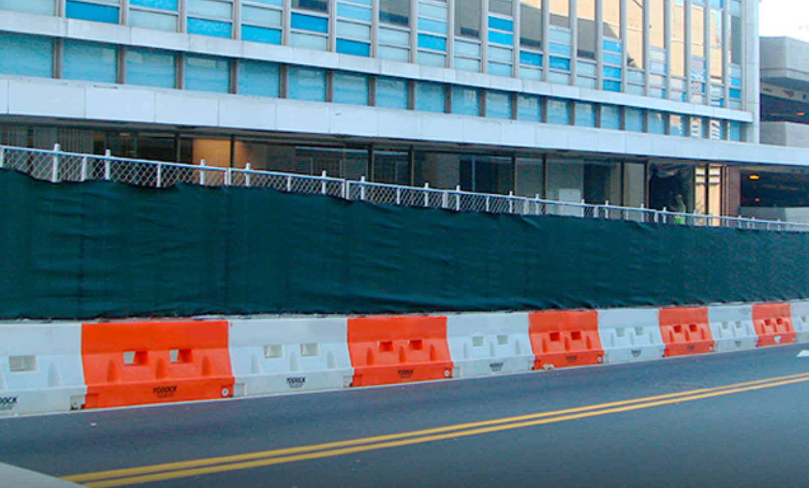 alternating white and orange plastic road barriers in front of a construction site