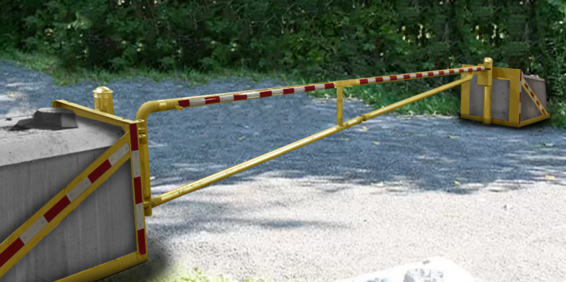 a yellow, red, and white vehicle gate closed across a gravel road